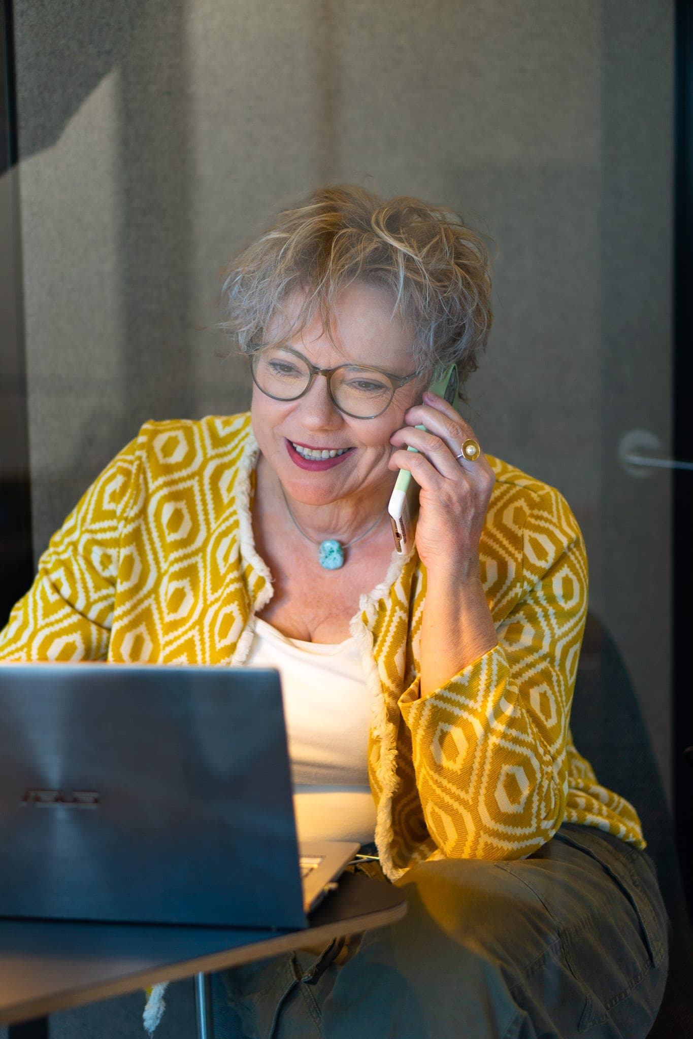 Britta, Beraterin der Junge Wilde Academy, lachend im Beratungsgespräch am Telefon mit Laptop